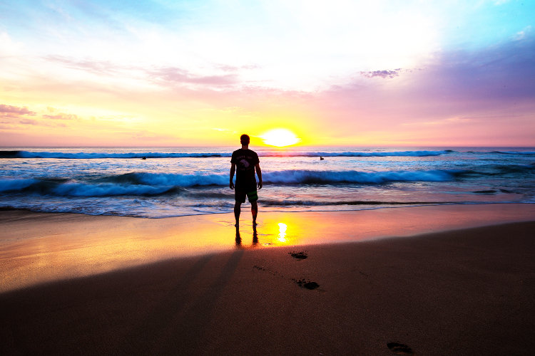 Man standing on beach at sunset