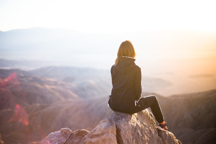 Woman sitting on mountain peak